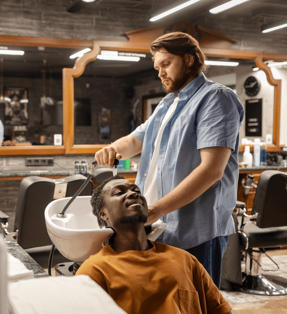 Barber washing a client’s hair at the sink